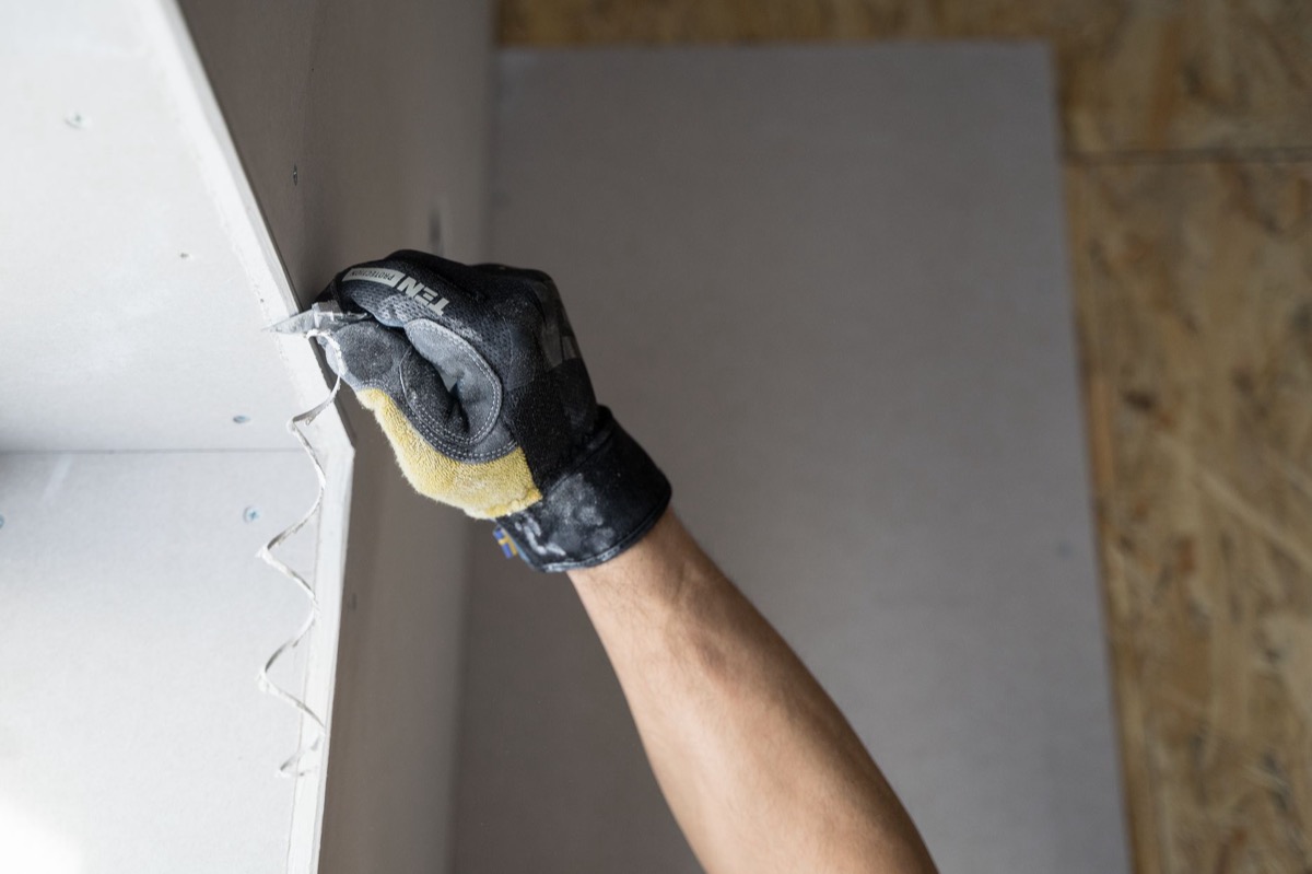Artisan posant et ajustant une plaque de placo sur un mur intérieur en rénovation